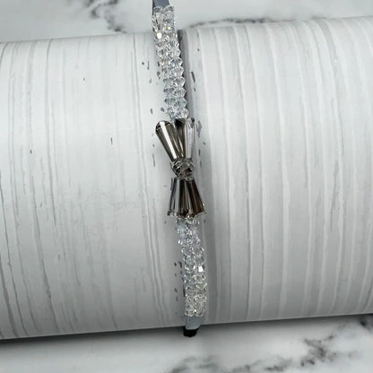 Elegant crystal bow hairbands with clear and silver beads on a white textured background