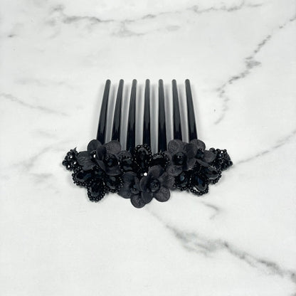 Black crystal studded comb clips with floral design on a white marble surface