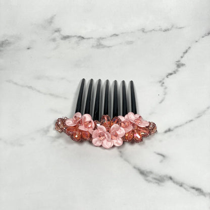 Black hair comb with pink flowers and crystal studded comb clips embellishments on marble surface