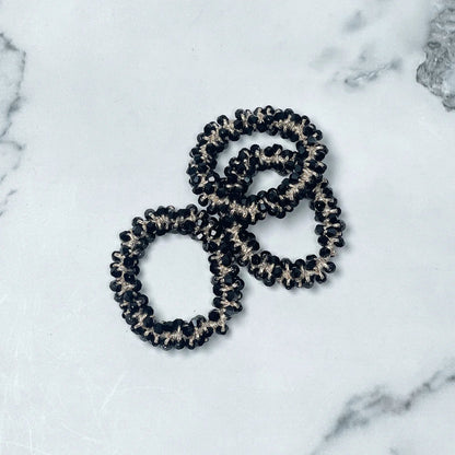 Black and silver crystal studded hair ties arranged on a white marble surface