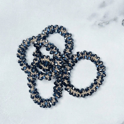 Black and clear crystal studded hair ties arranged in a cluster on a light surface