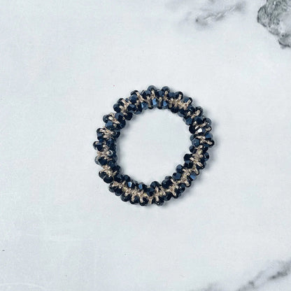 Black crystal studded hair ties with gold accents on white marble background