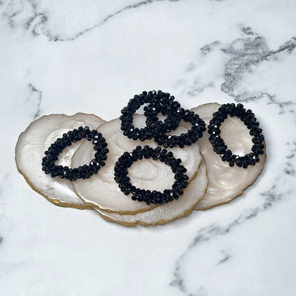 Set of black crystal studded hair ties displayed on white agate slices with gold edges