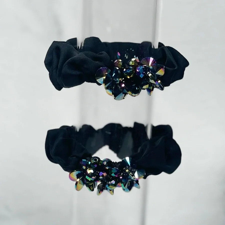 Black crystal studded hair ties with multicolor sparkling crystals on a reflective surface