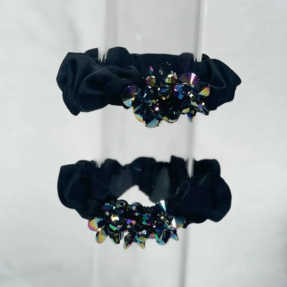 Black crystal studded hair ties with multicolor sparkling crystals on a reflective surface