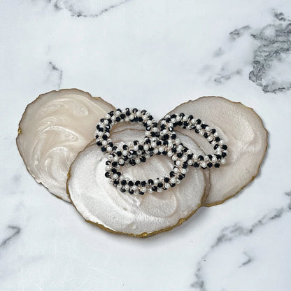 Black and white crystal studded hair ties displayed on decorative white and beige agate coasters