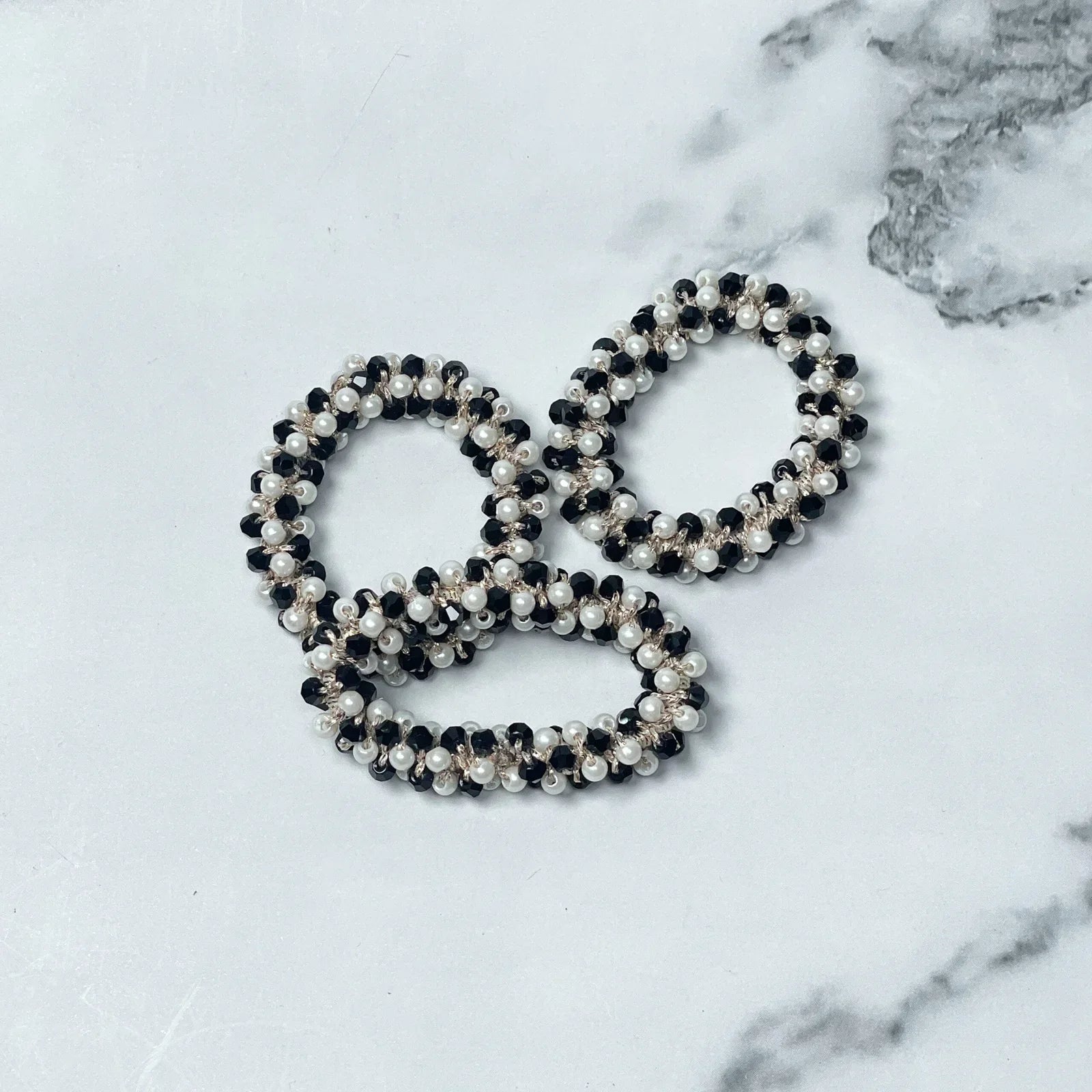 Black and white pearl crystal studded hair ties arranged on white marble surface