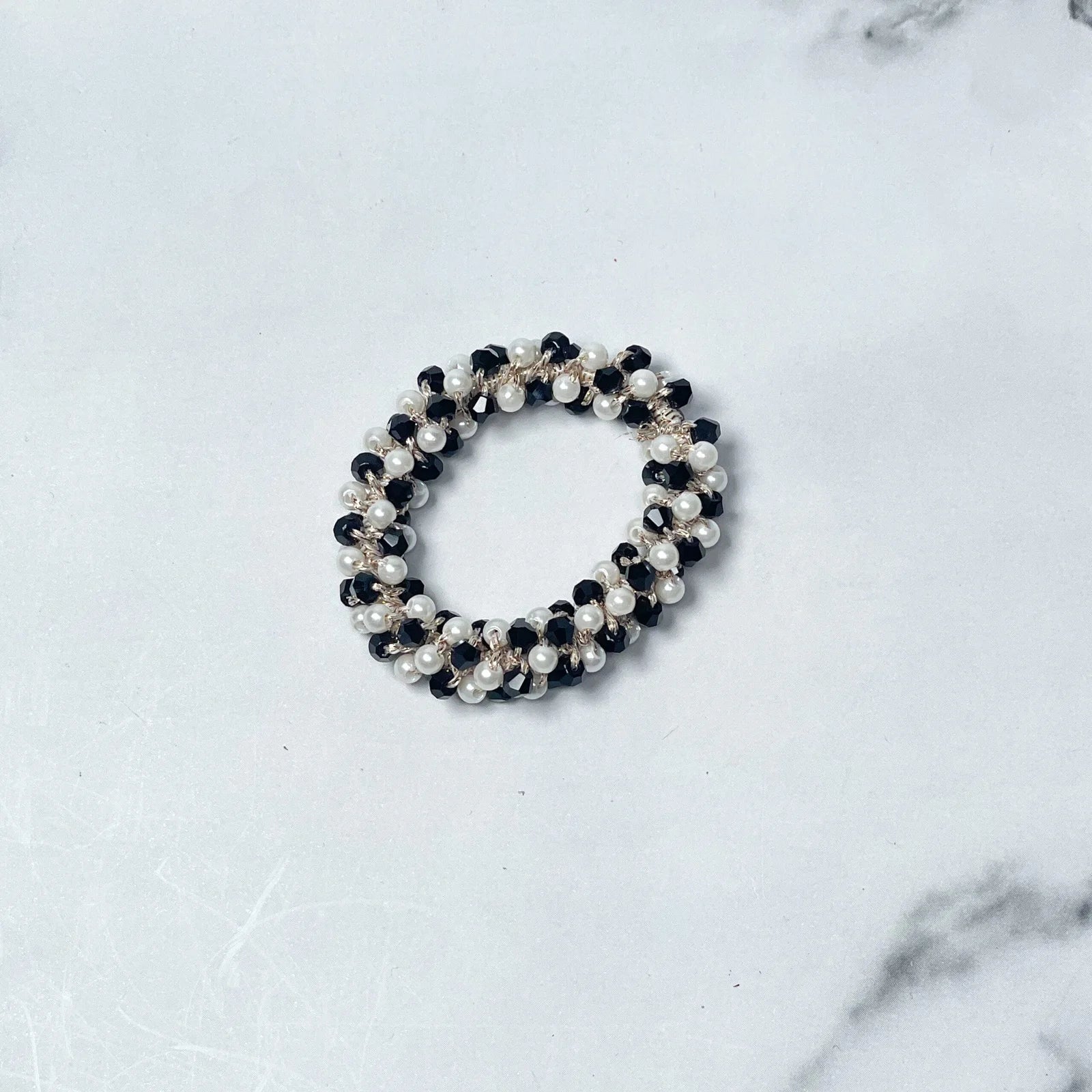 Black and white crystal studded hair ties featuring pearl and bead embellishments on white marble background