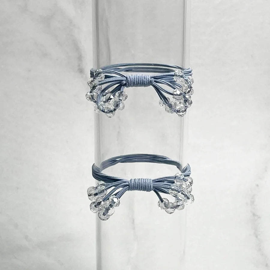 Blue crystal studded hair ties bow with clear bead accents on transparent stand