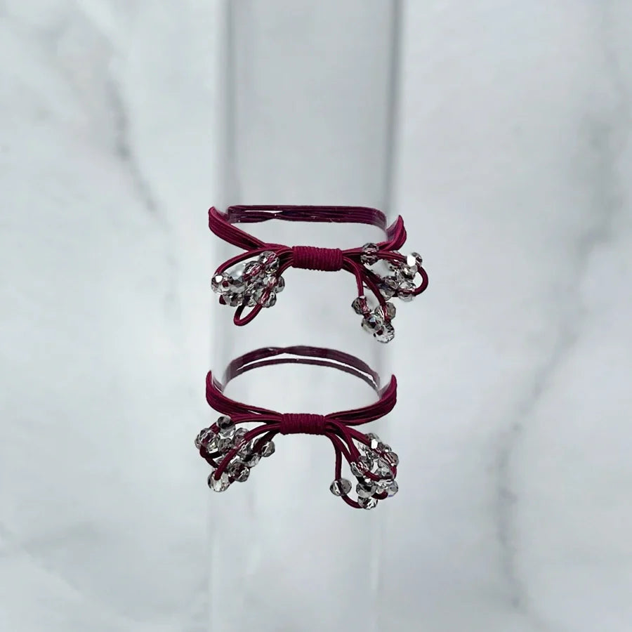 Crystal studded hair ties bow in dark red with decorative crystal accents on a clear display