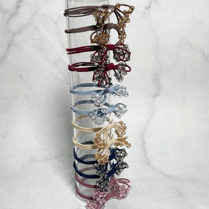 Set of crystal studded hair ties bow in various colors displayed on clear stand