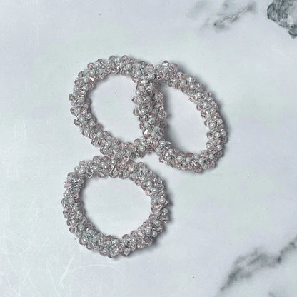 Set of three crystal studded hair ties with clear beads on a white marble surface