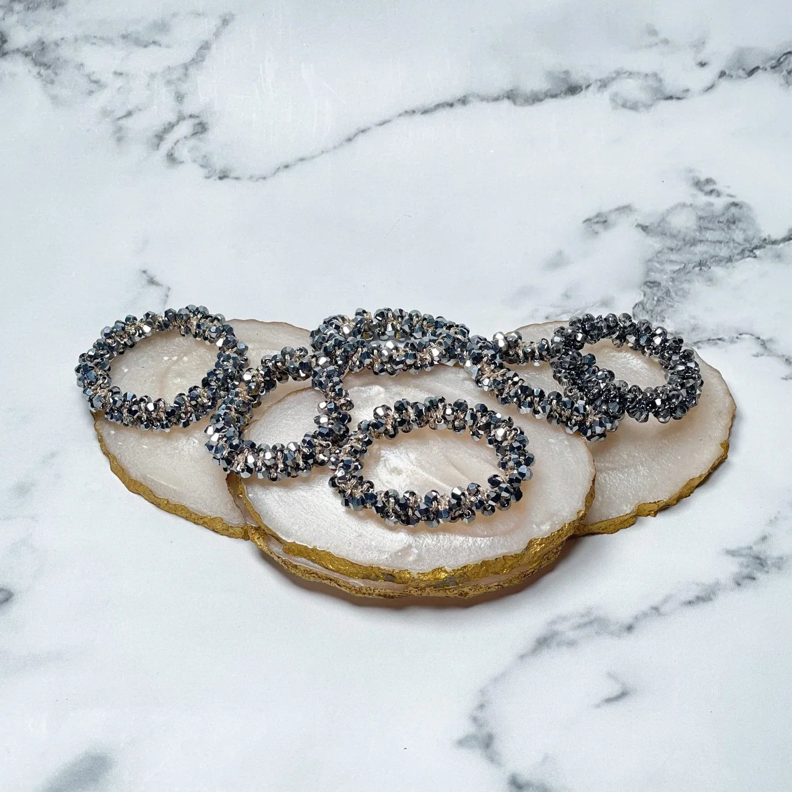 Set of crystal studded hair ties with black and silver crystals on a white marble background