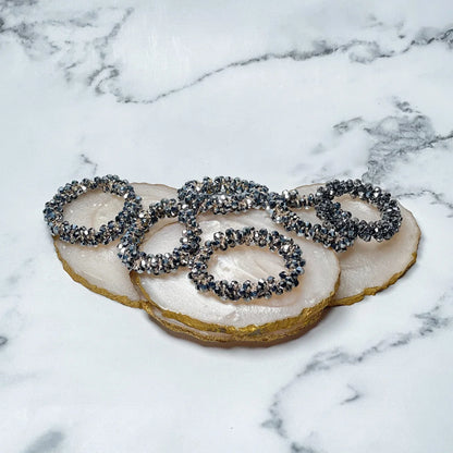 Set of crystal studded hair ties with black and silver crystals on a white marble background