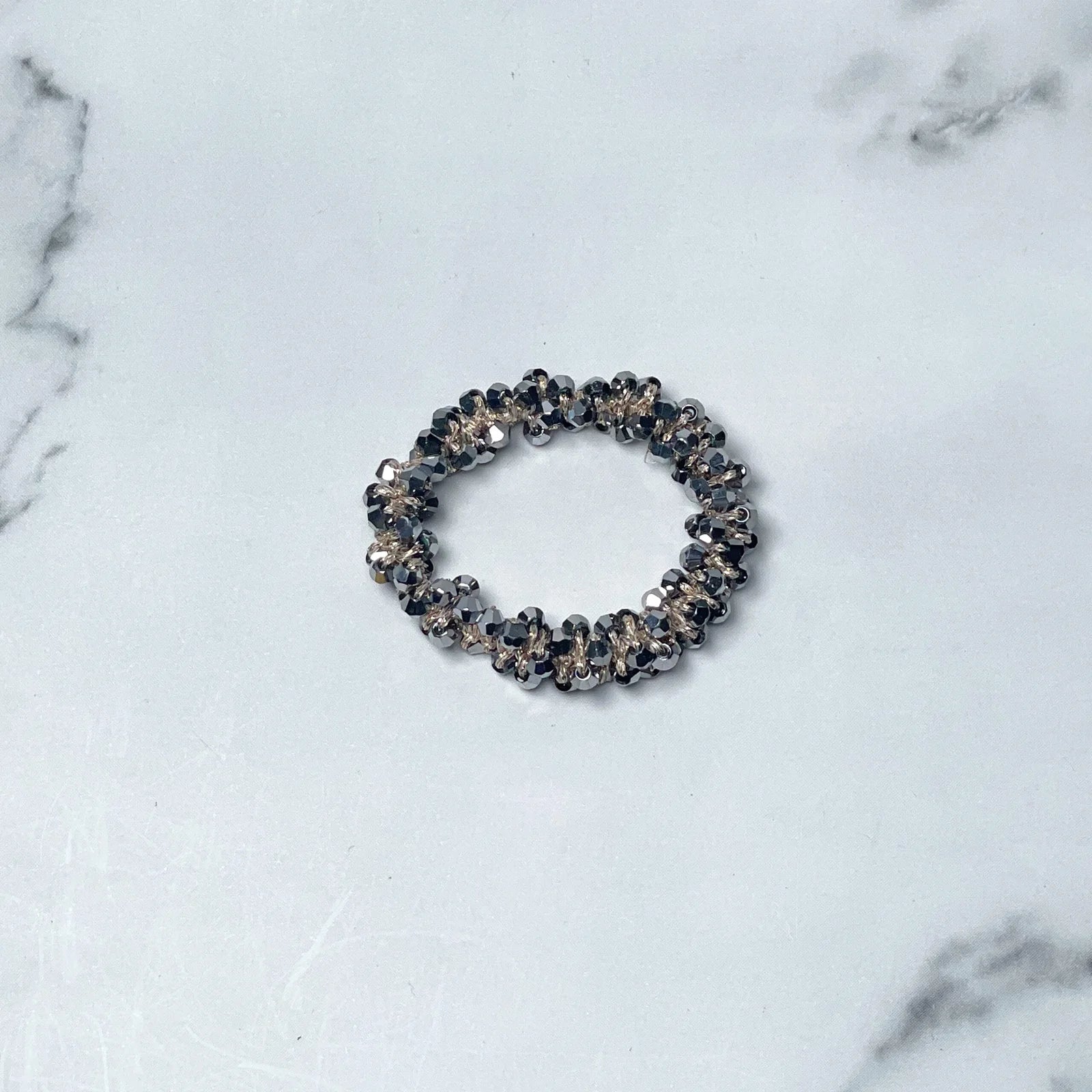 Black crystal studded hair ties with sparkling beads on a white marble surface