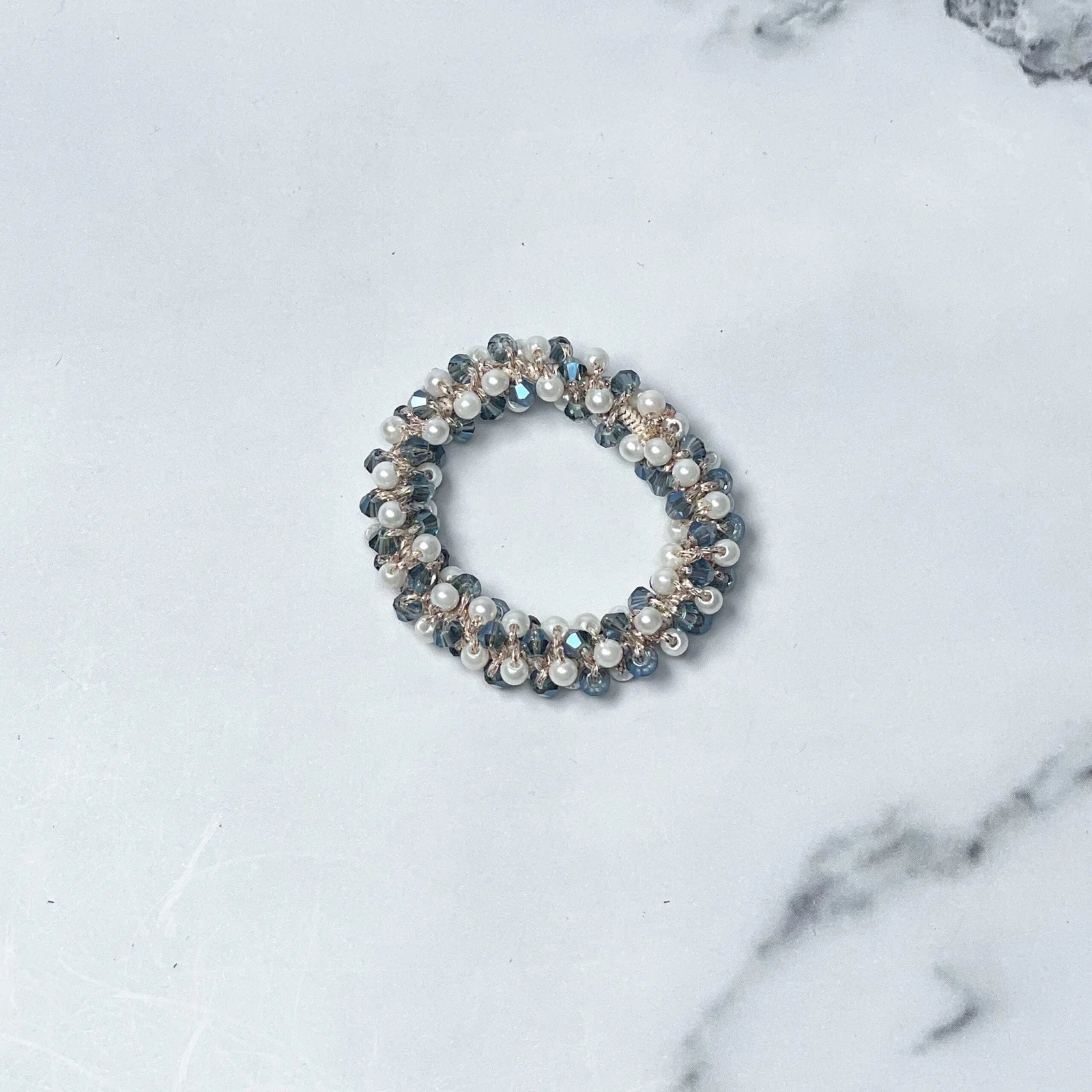 Crystal studded hair ties with pearl and bead embellishments on marble surface