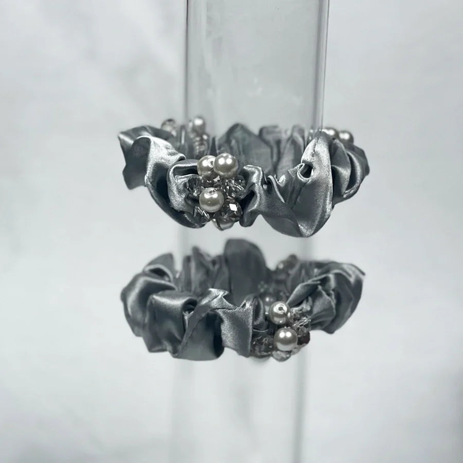 Silver crystal studded hair ties with pearl and rhinestone accents on shiny fabric scrunchies