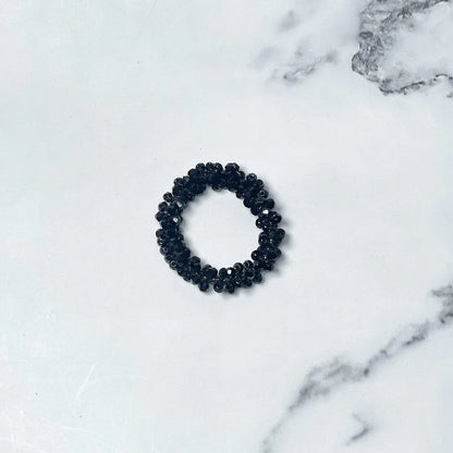 Black crystal studded hair ties with glossy beads on white marble background