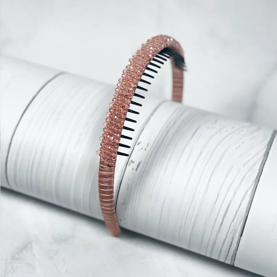 Rose gold crystal studded headbands for women displayed on textured white surface