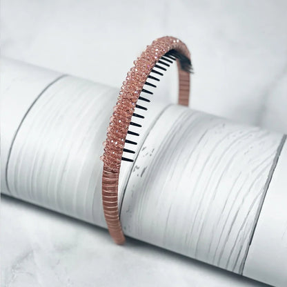 Rose gold crystal studded headbands for women displayed on textured white surface