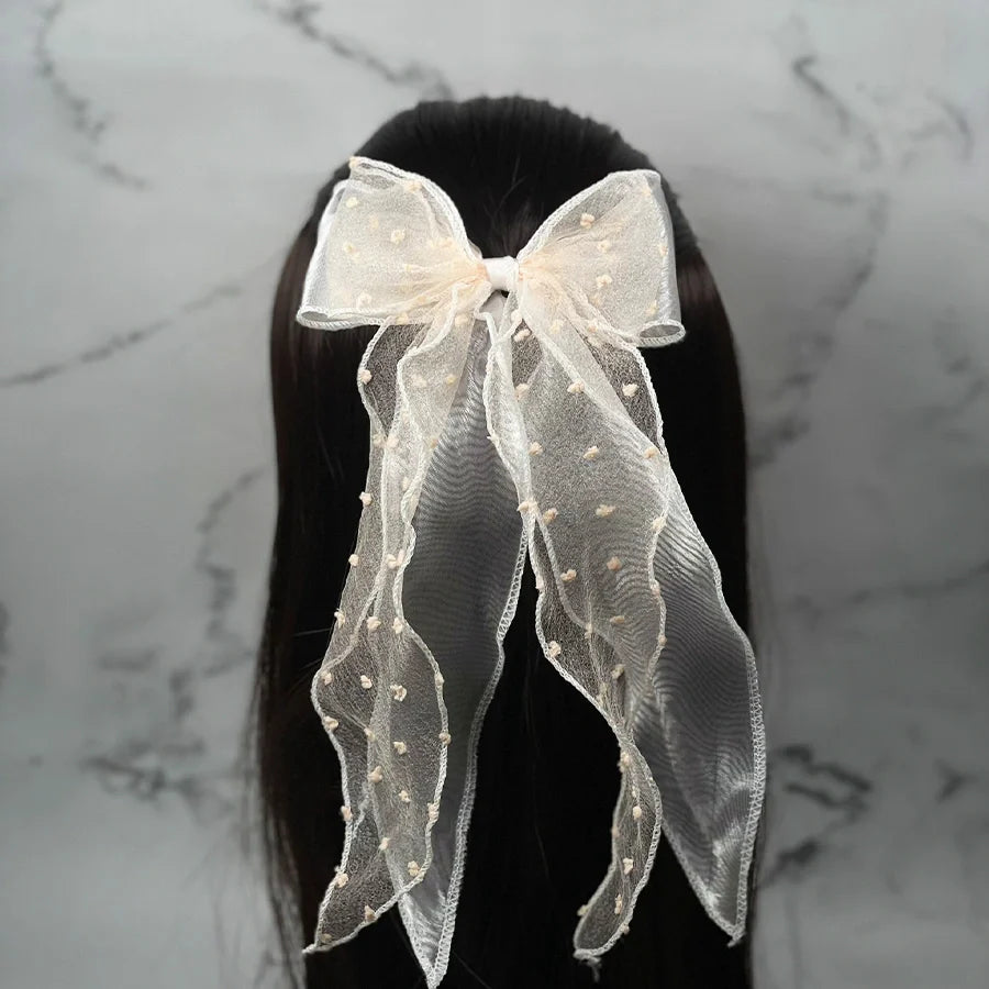 Dotted organza bow hair pin in cream color worn on dark hair with long flowing tails