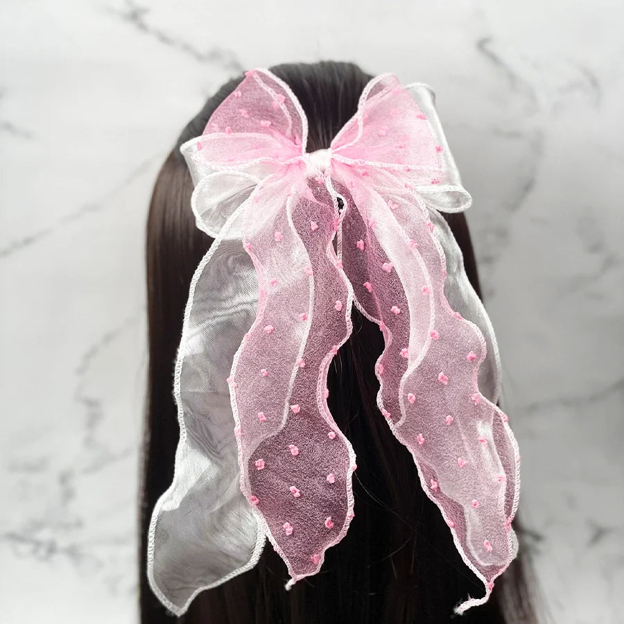 Pink and white dotted organza bow hair pin styled on dark straight hair with long tails