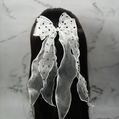 White dotted organza bow hair pin with long flowing tails attached to dark hair