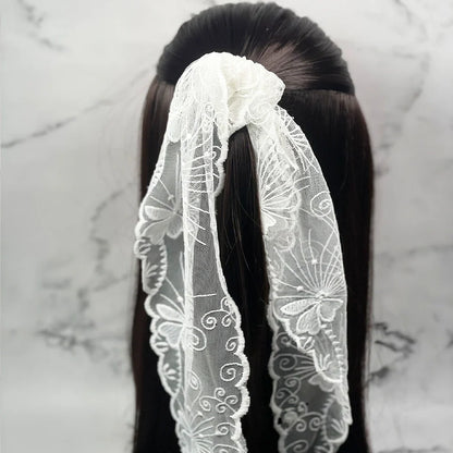 White embroidered lacy scarf tied in hair with intricate floral patterns and delicate fabric