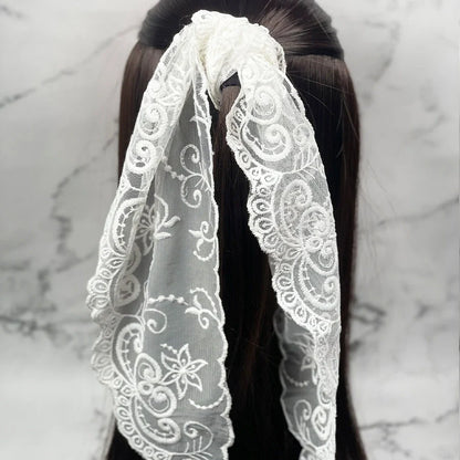 White embroidered lacy scarf tied around dark hair showcasing delicate floral lace patterns