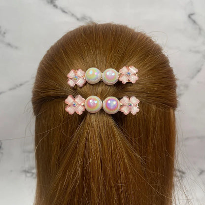 Fancy pearl flower hair pins with pink floral designs worn on light brown hair