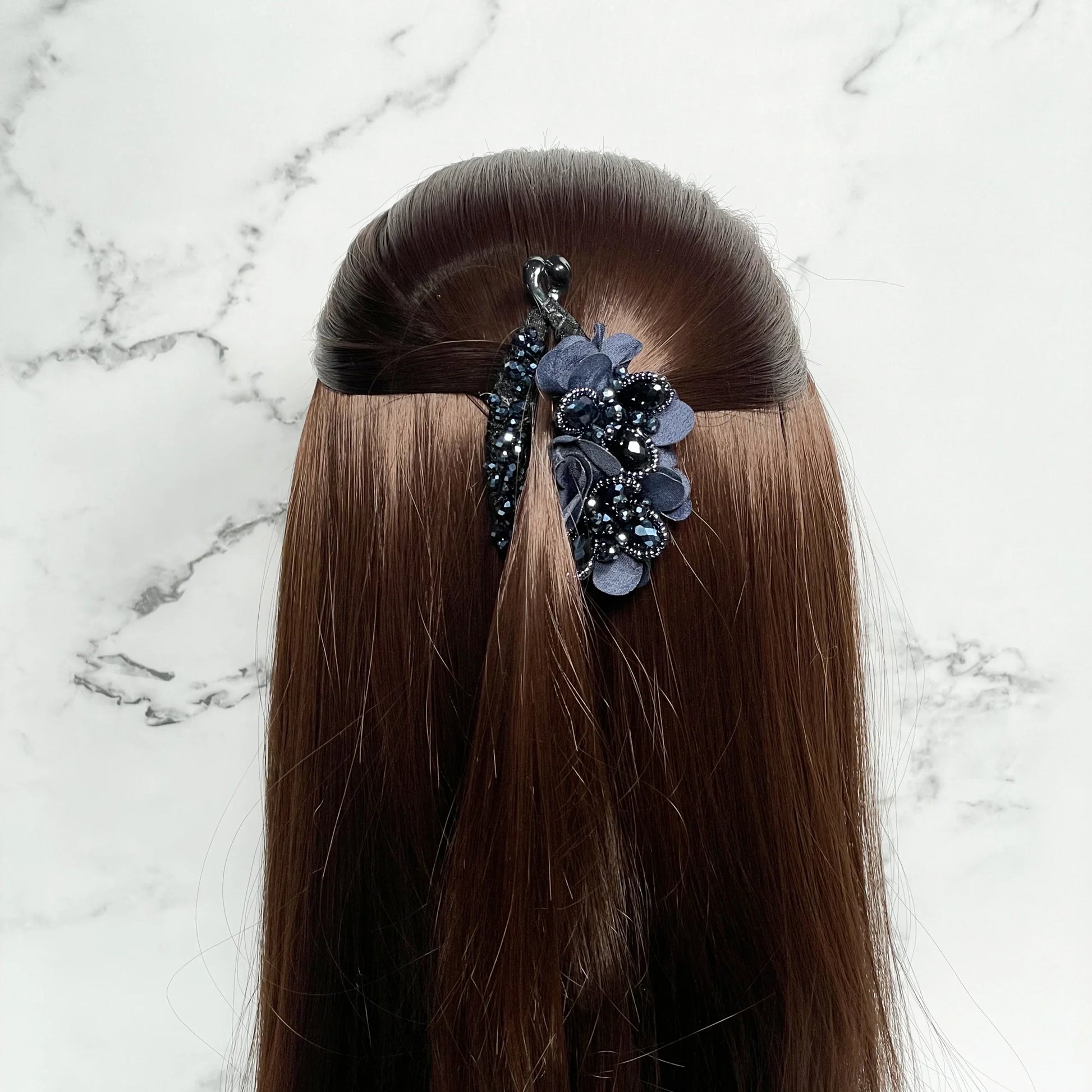 Floral and Crystal Studded Banana Clips securing half-up hairstyle on brown hair against marble background