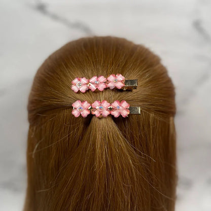 Pink floral hair pins for women decorated with rhinestones on brown hair