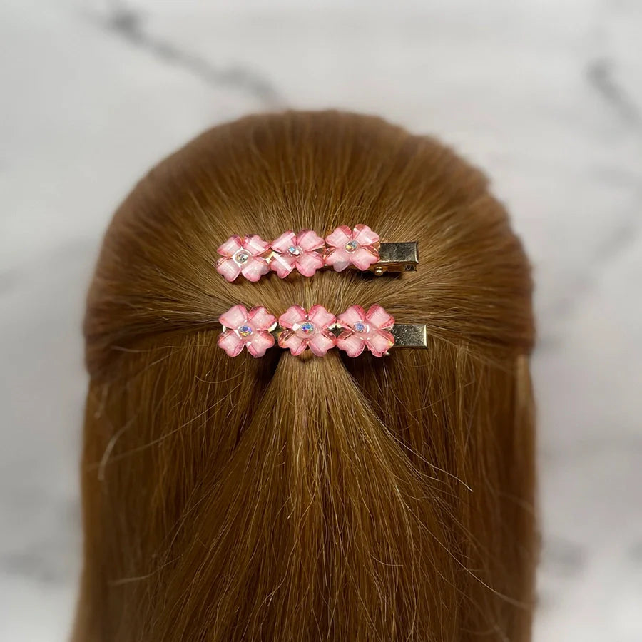 Pink floral hair pins for women with rhinestone accents styled in brown hair half updo