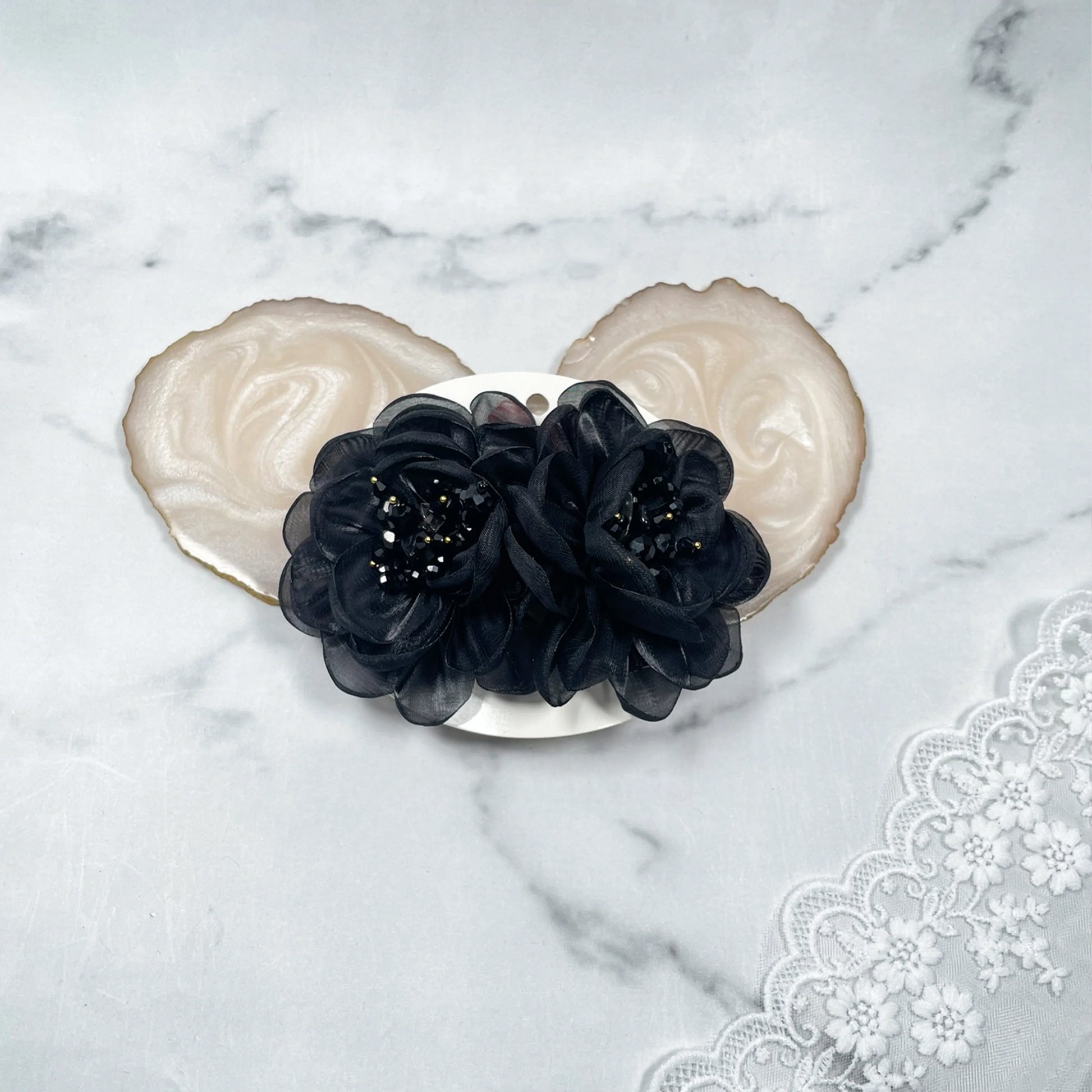 Black floral organza hair pins with delicate bead details on a white background with lace