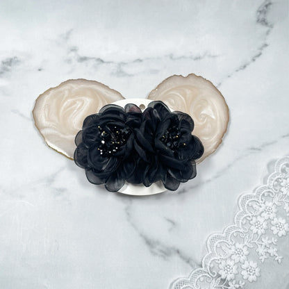 Black floral organza hair pins with delicate bead details on a white background with lace