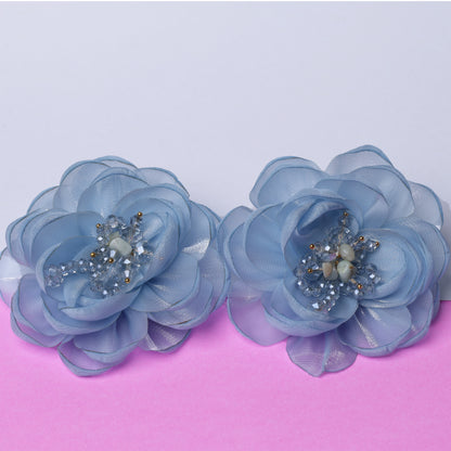 Two blue floral organza hair pins with bead and crystal centers on a pink and white background