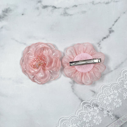Pink floral organza hair pins with delicate translucent petals and metal clip on marble background
