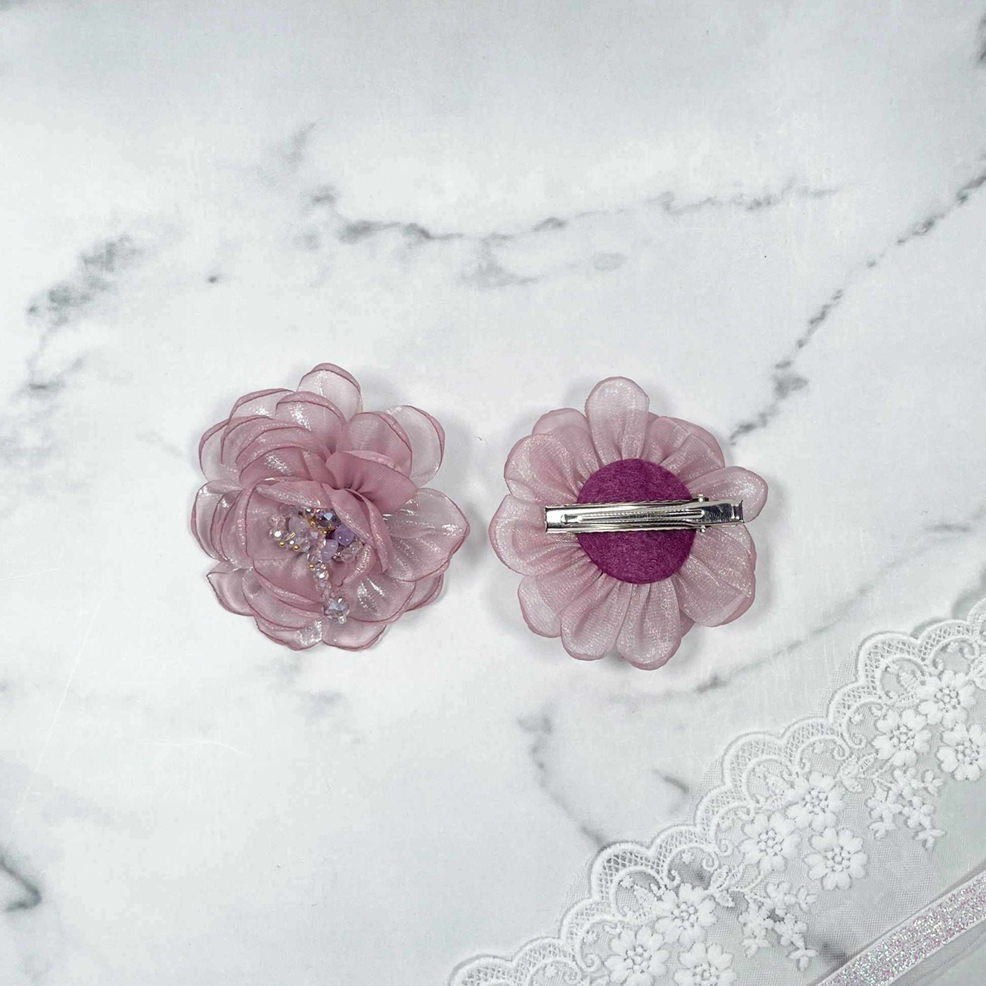 Purple floral organza hair pins with delicate petals and bead accents on marble background