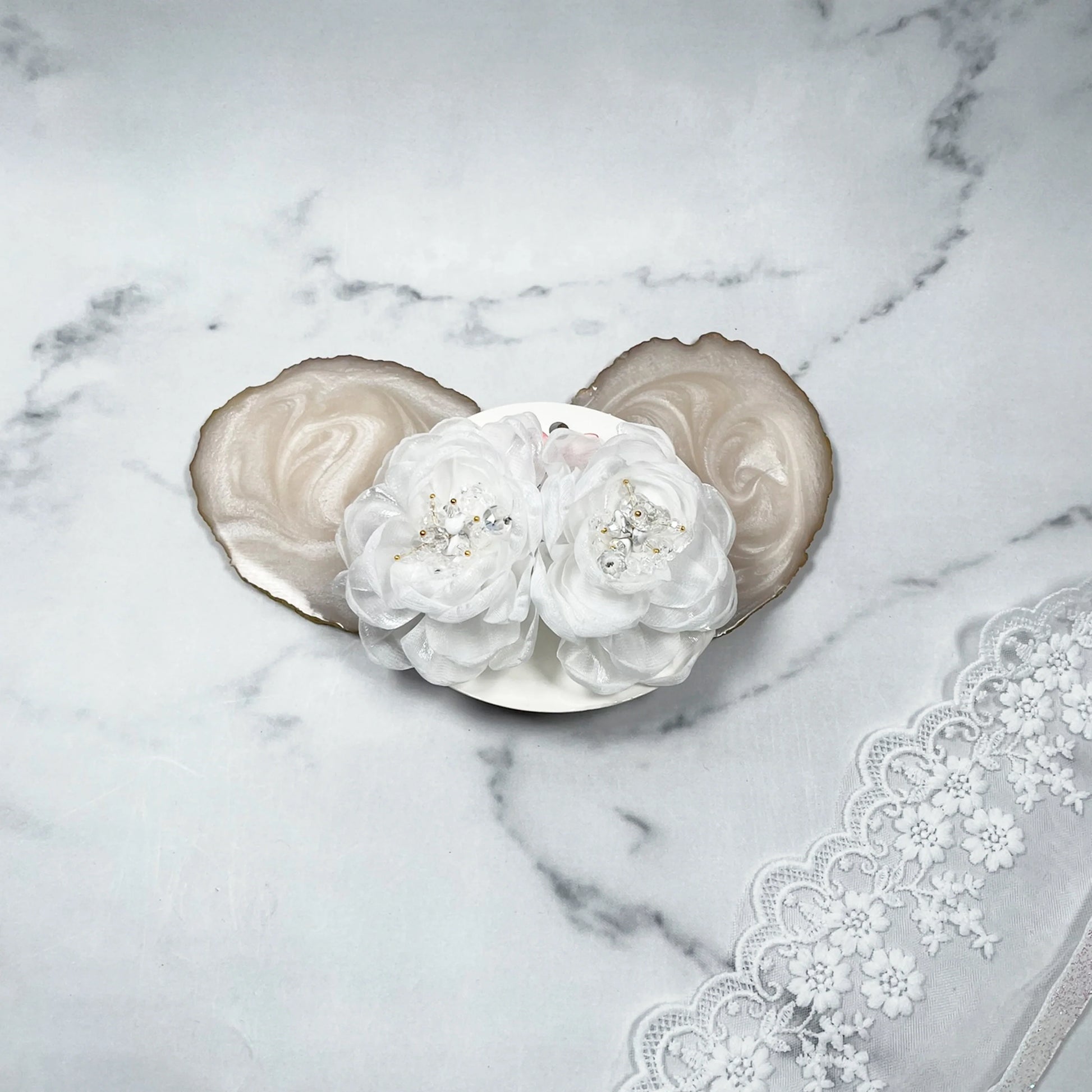 White floral organza hair pins with delicate bead detailing on a marble background with lace fabric