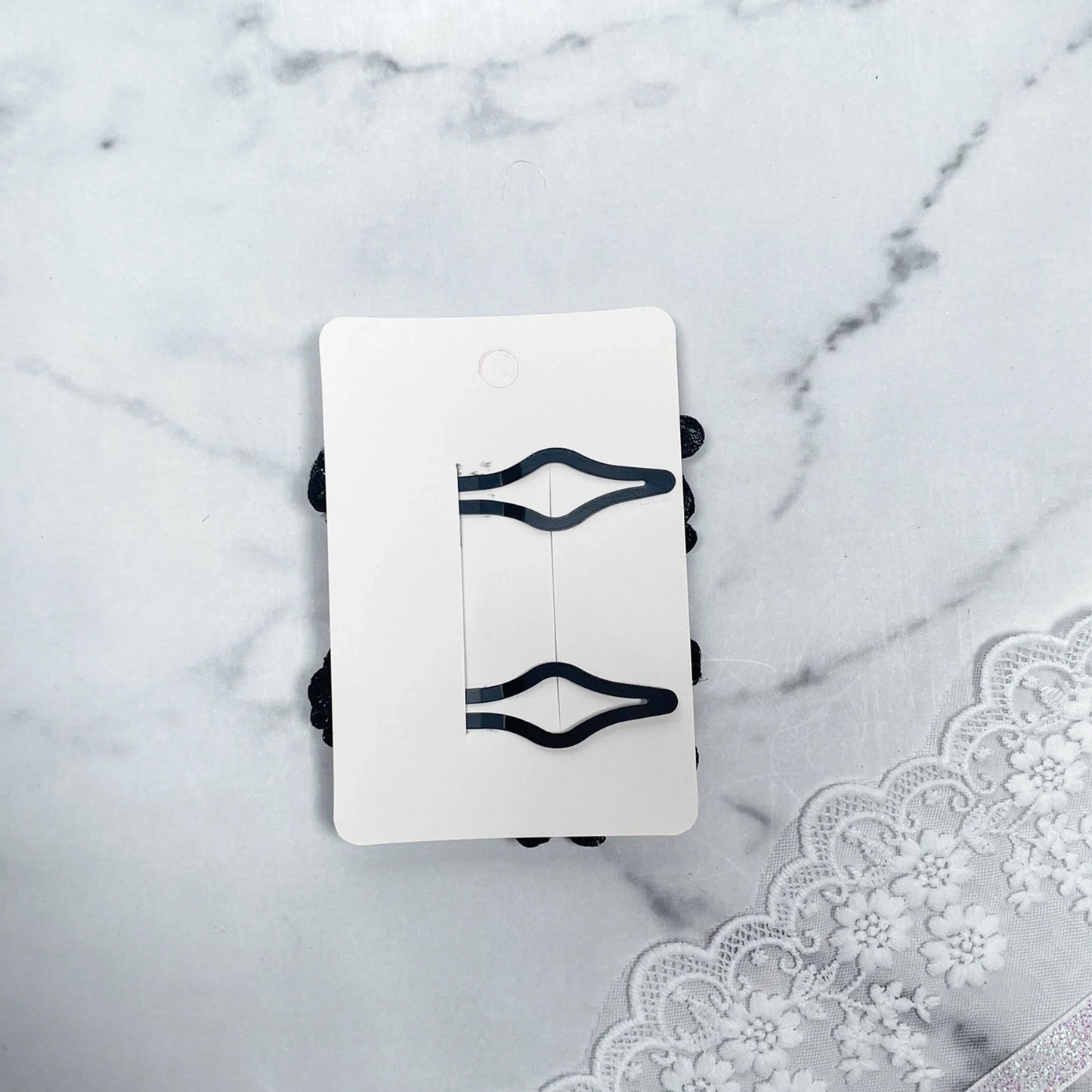 Black flower crystal hair pins displayed on white card with lace fabric background