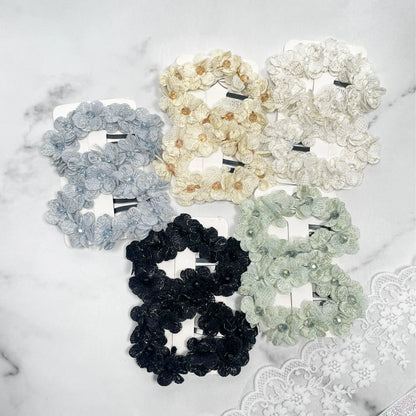 Set of flower crystal hair pins in various colors including black, white, cream, gray, and green on a marble surface