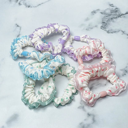 Colorful frill polka dot hair ties with delicate lace edges in pastel shades on marble background