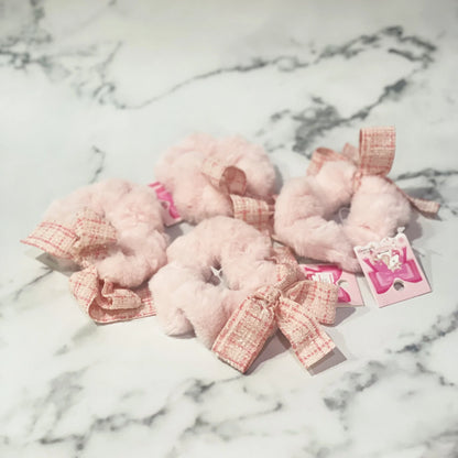 Pink fur scrunchie with check ribbon displayed on marble surface from mydevelopmentstor