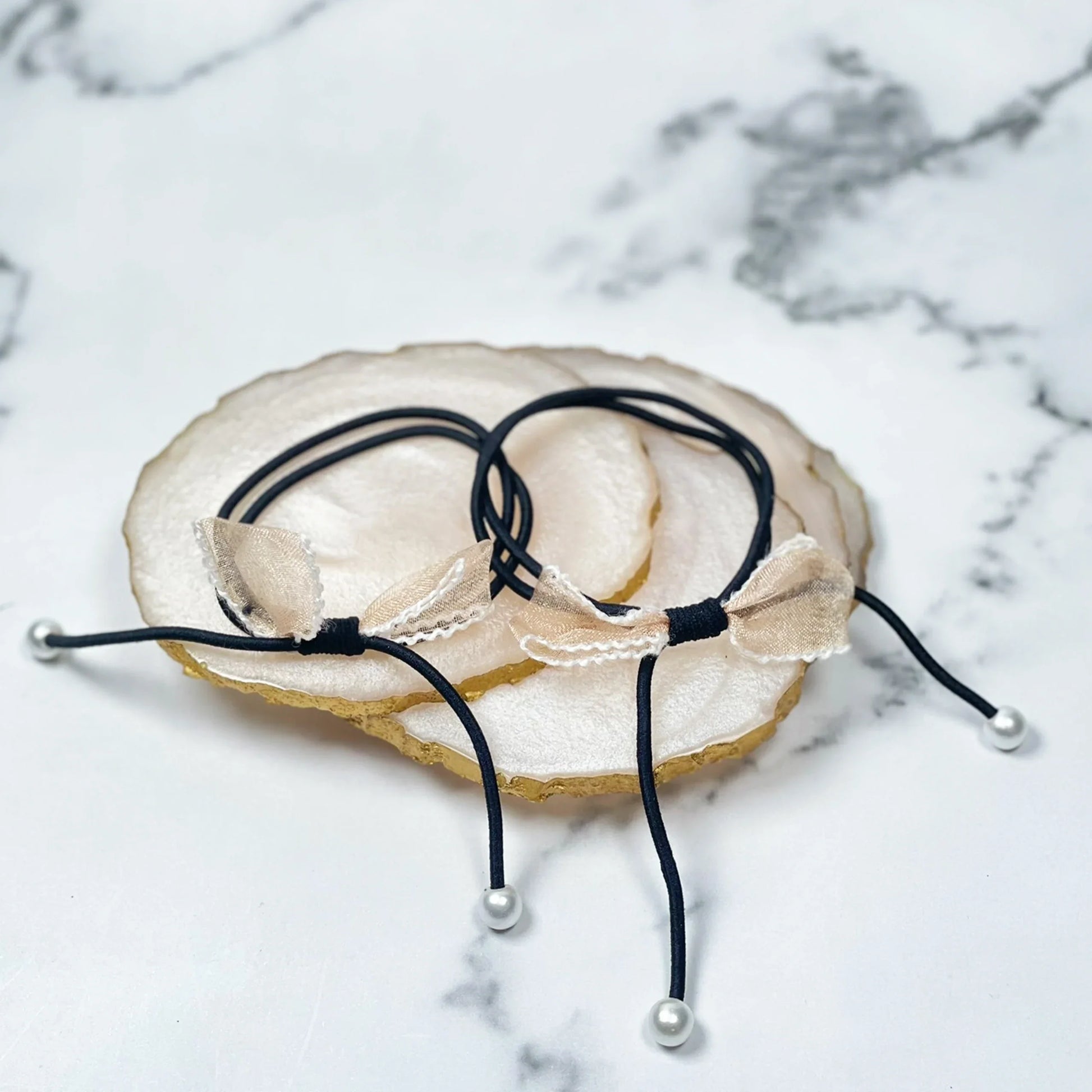 Black hair ties with bows and beads featuring delicate fabric bows and pearl-like beads