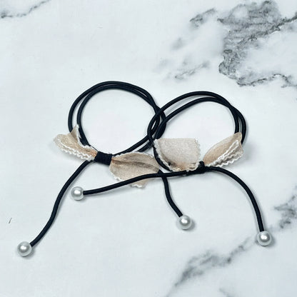 Black hair ties with bows and beads featuring beige fabric bows and white pearl-like beads