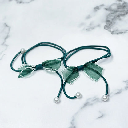 Green hair ties with bows and beads on a white marble surface from mydevelopmentstor