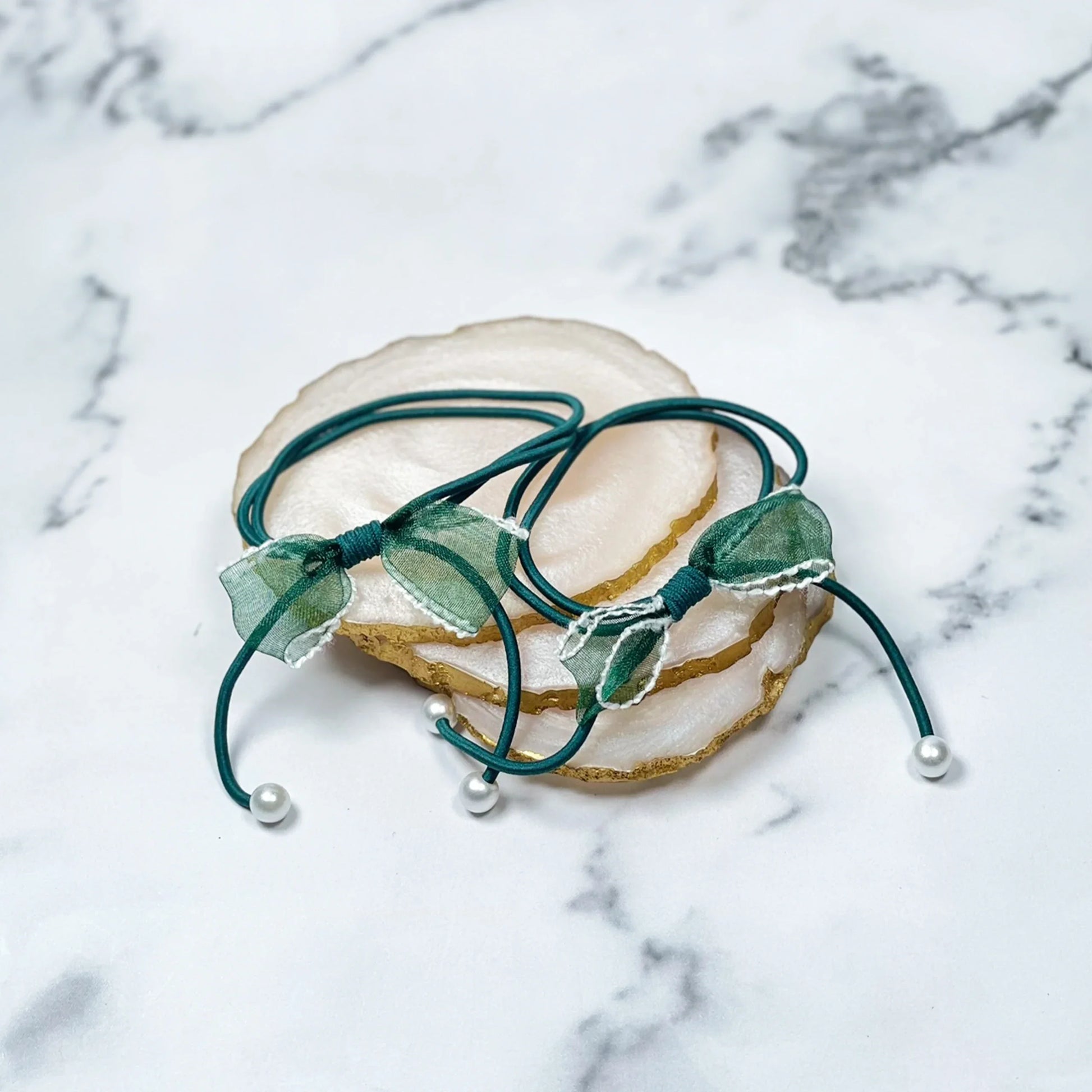 Green hair ties with bows and beads featuring delicate fabric bows and pearl-like beads on elastic bands