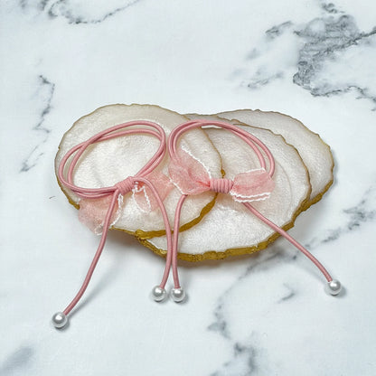 Pink hair ties with bows and beads displayed on white agate slices with gold edges