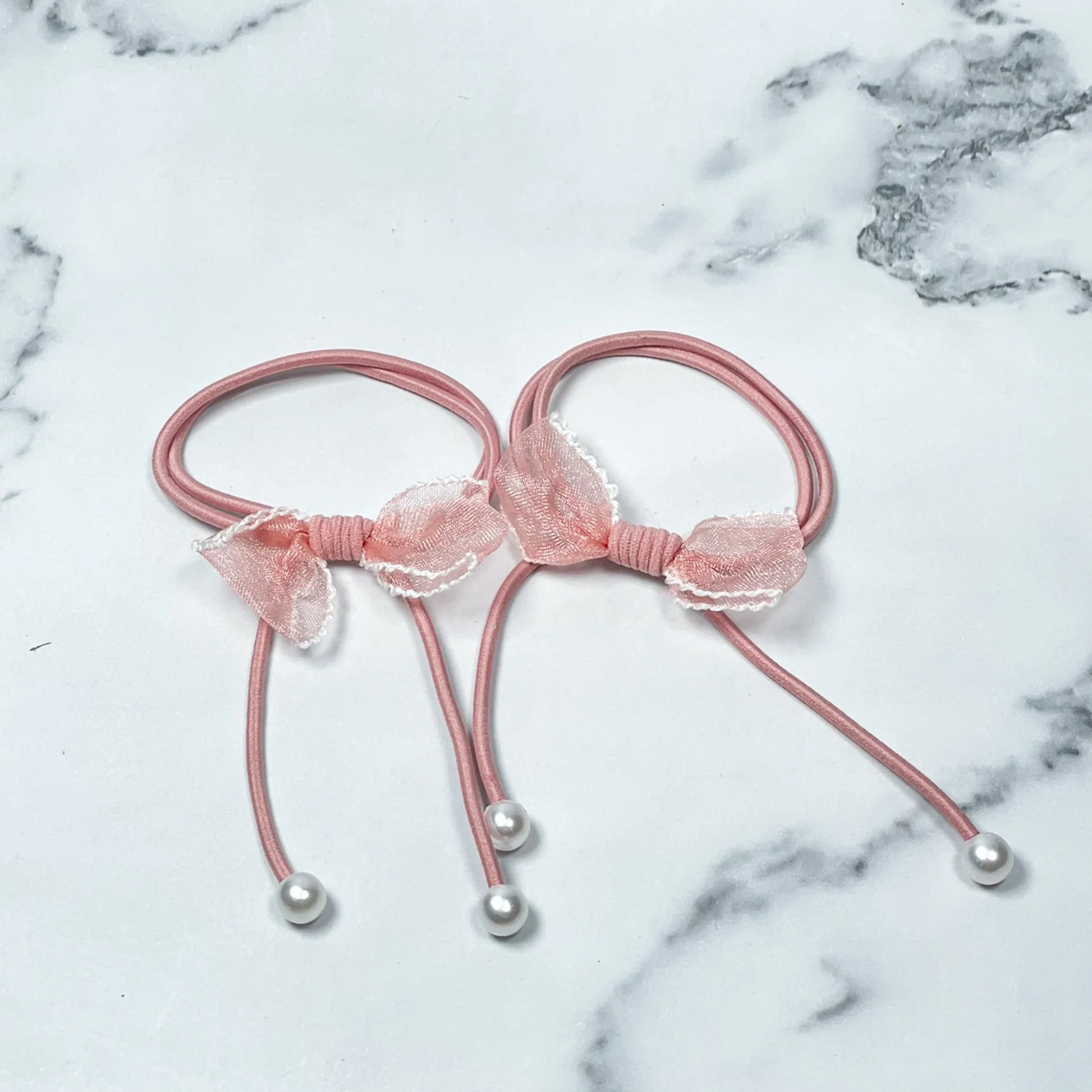 Pink hair ties with bows and beads featuring delicate lace bows and pearl bead ends on elastic bands