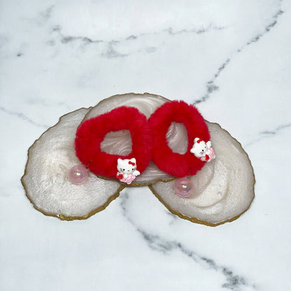 Red kids furry hair ties with cute white bear charms displayed on marble coasters